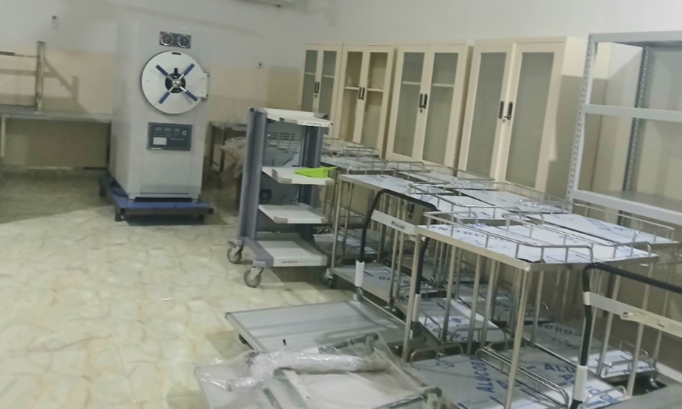 Room with medical equipment, including sterilizers and metal carts, neatly arranged.