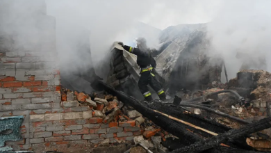 Firefighter amidst smoke, navigating through the debris of a damaged building.