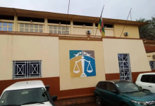 Building with a justice scale mural, flag on top, and parked cars in front.