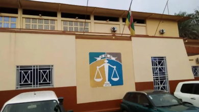 Building with a justice scale mural, flag on top, and parked cars in front.