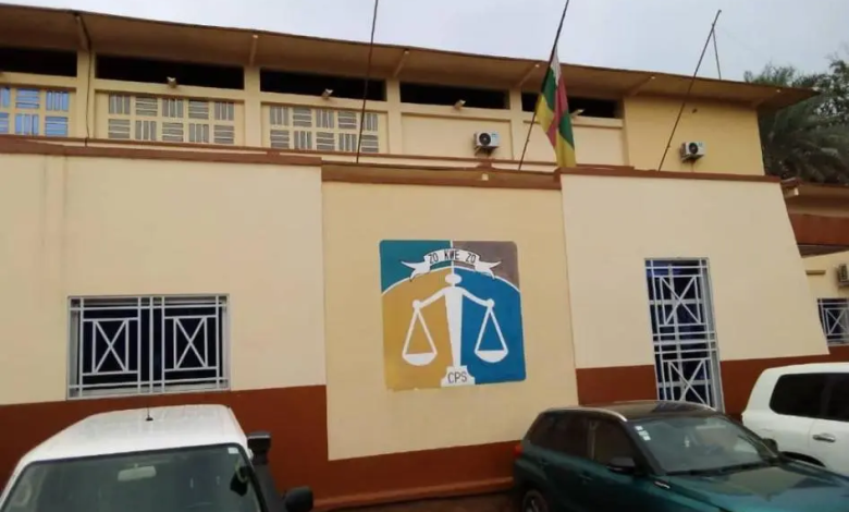 Building with a justice scale mural, flag on top, and parked cars in front.