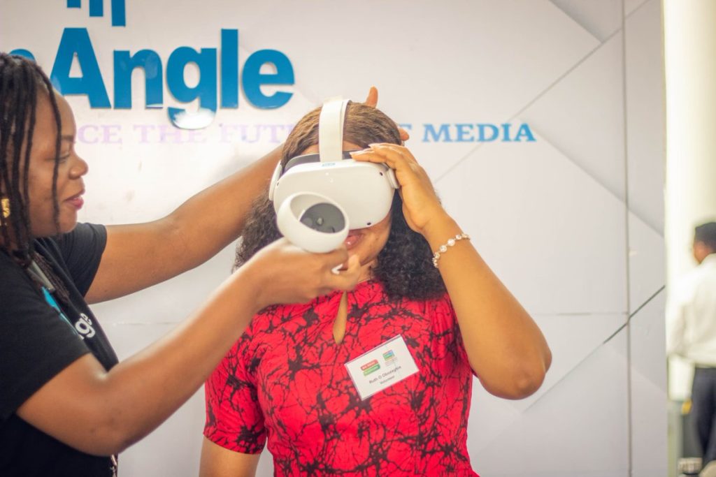 A woman helps another adjust a VR headset at a tech event.