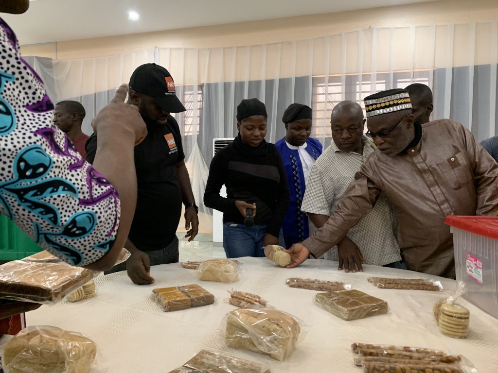 Group of people examining various packaged snacks on a table indoors.