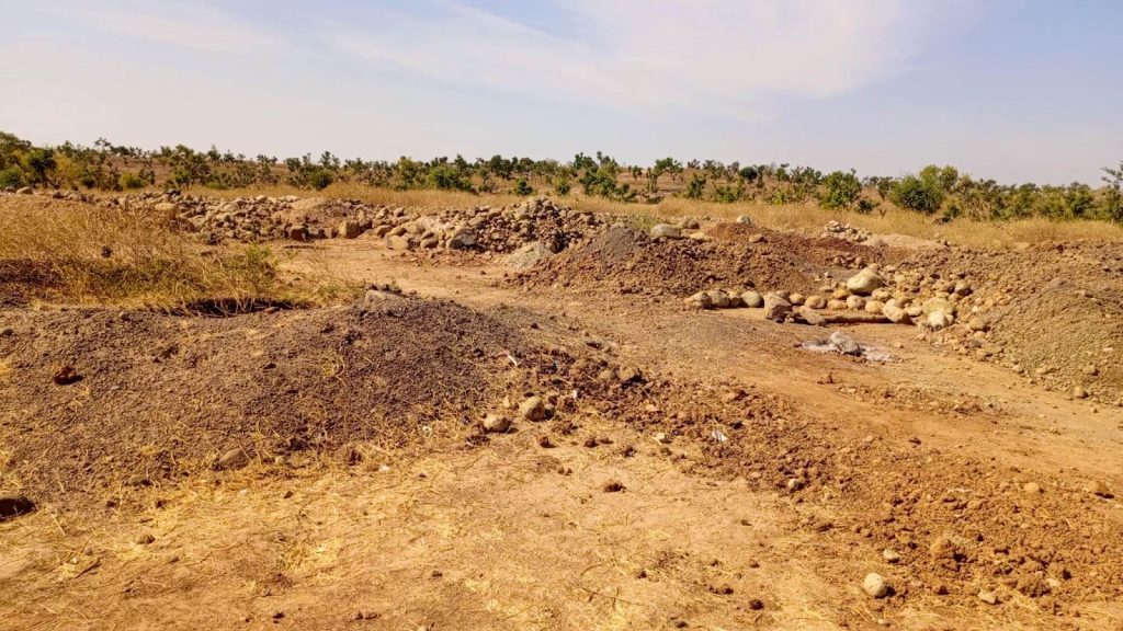 Dry landscape with scattered rocks and sparse vegetation under a clear sky.