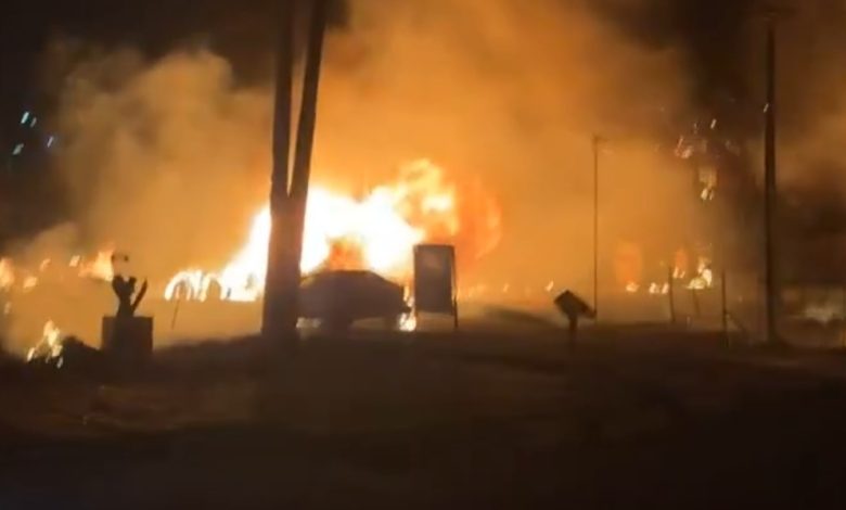 Large fire burning intensely at night, with thick smoke billowing into the dark sky.