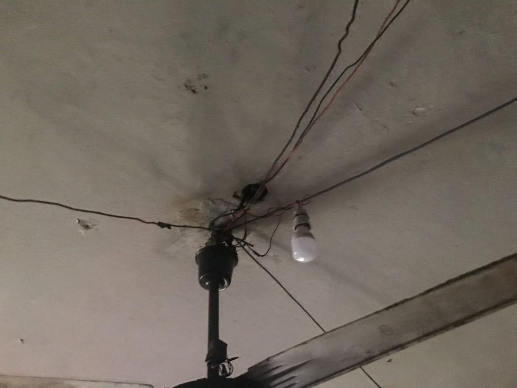 Ceiling with visible wiring, a single light bulb, and a ceiling fan.