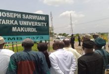 People gathered around the Joseph Sarwuan Tarka University Makurdi sign.