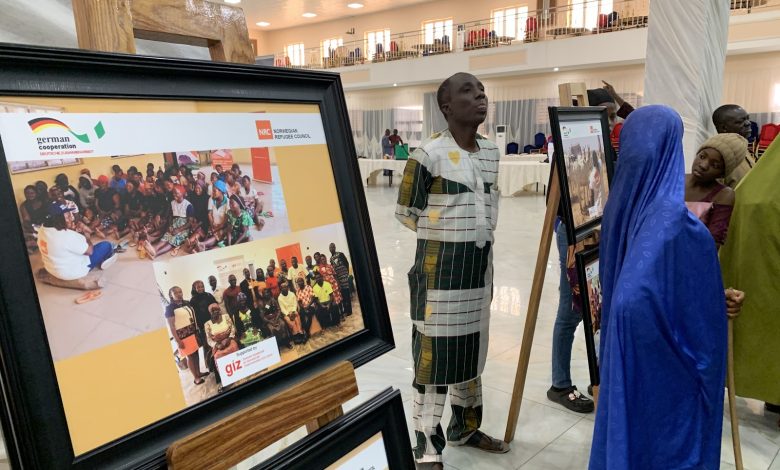 People viewing framed photos at an exhibition in a well-lit hall.