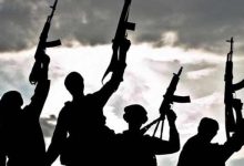 Silhouetted figures raise rifles against a cloudy sky background.