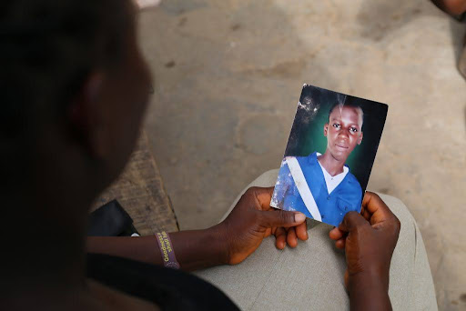 Person holding a photo of a child wearing a blue and white outfit.