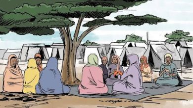 A group of people in colorful clothing sit under a tree near tents, engaging in conversation.