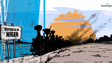 Silhouetted group near "Republic of Niger" sign, facing a smoky horizon under a colorful sky.