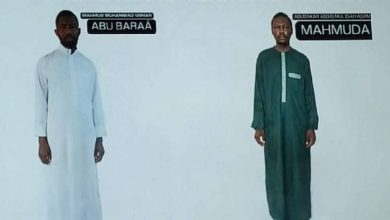 Two men in traditional clothing stand against a white background, one in a white robe labeled "Abu Baraa" and the other in green labeled "Mahmuda."