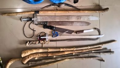 Various tools and improvised weapons, including sticks, machetes, scissors, and a slingshot, arranged on a tiled floor.