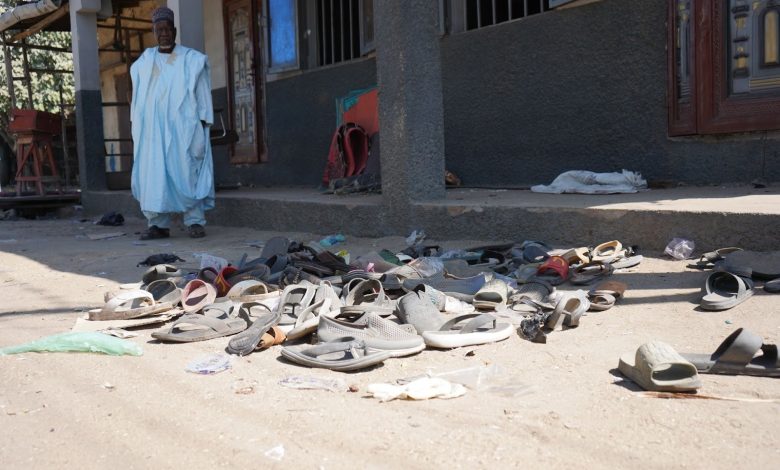 Sandals scattered on the ground outside a building with a person standing near the entrance.