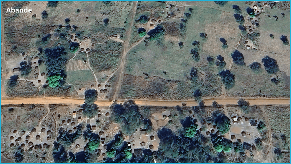 Aerial view of a rural landscape with scattered round huts, trees, and dirt roads in Abande.