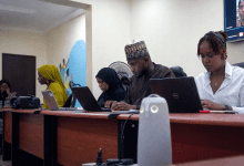Four people working on laptops at a conference table, focused and engaged in a meeting.