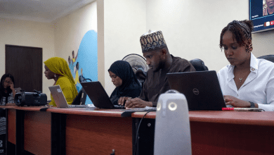 Four people working on laptops at a conference table, focused and engaged in a meeting.
