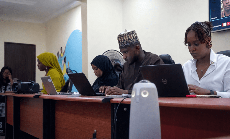 Four people working on laptops at a conference table, focused and engaged in a meeting.