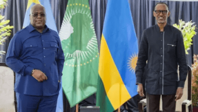 Two men stand in front of African Union and national flags, engaged in a formal setting.