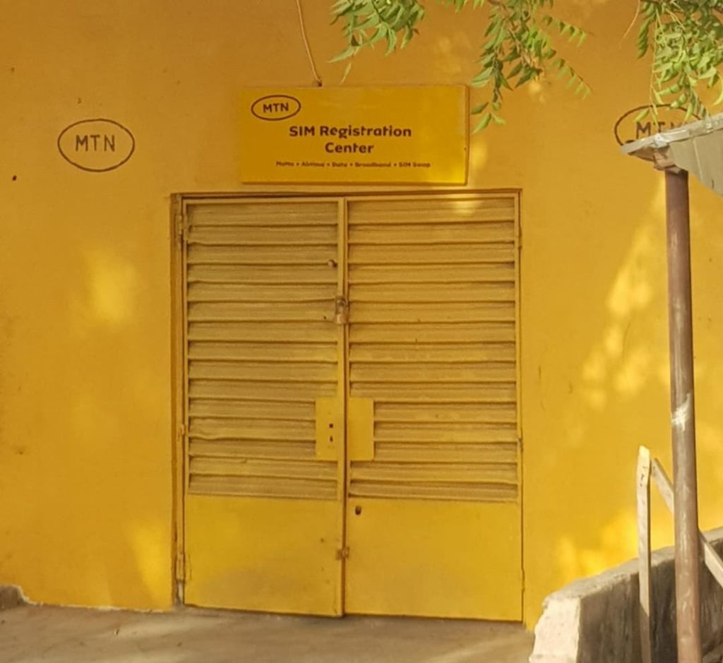 Yellow building with closed shutters labeled "SIM Registration Center" and "MTN" logos.