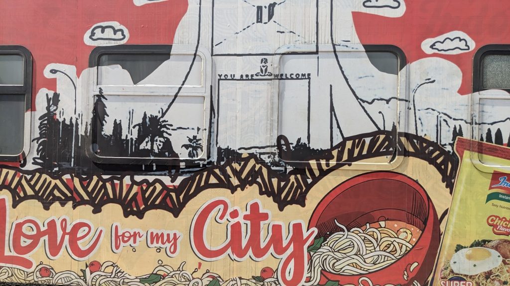 Colorful mural on a vehicle promotes instant noodles with city skyline, pasta, and "Love for my City" text.