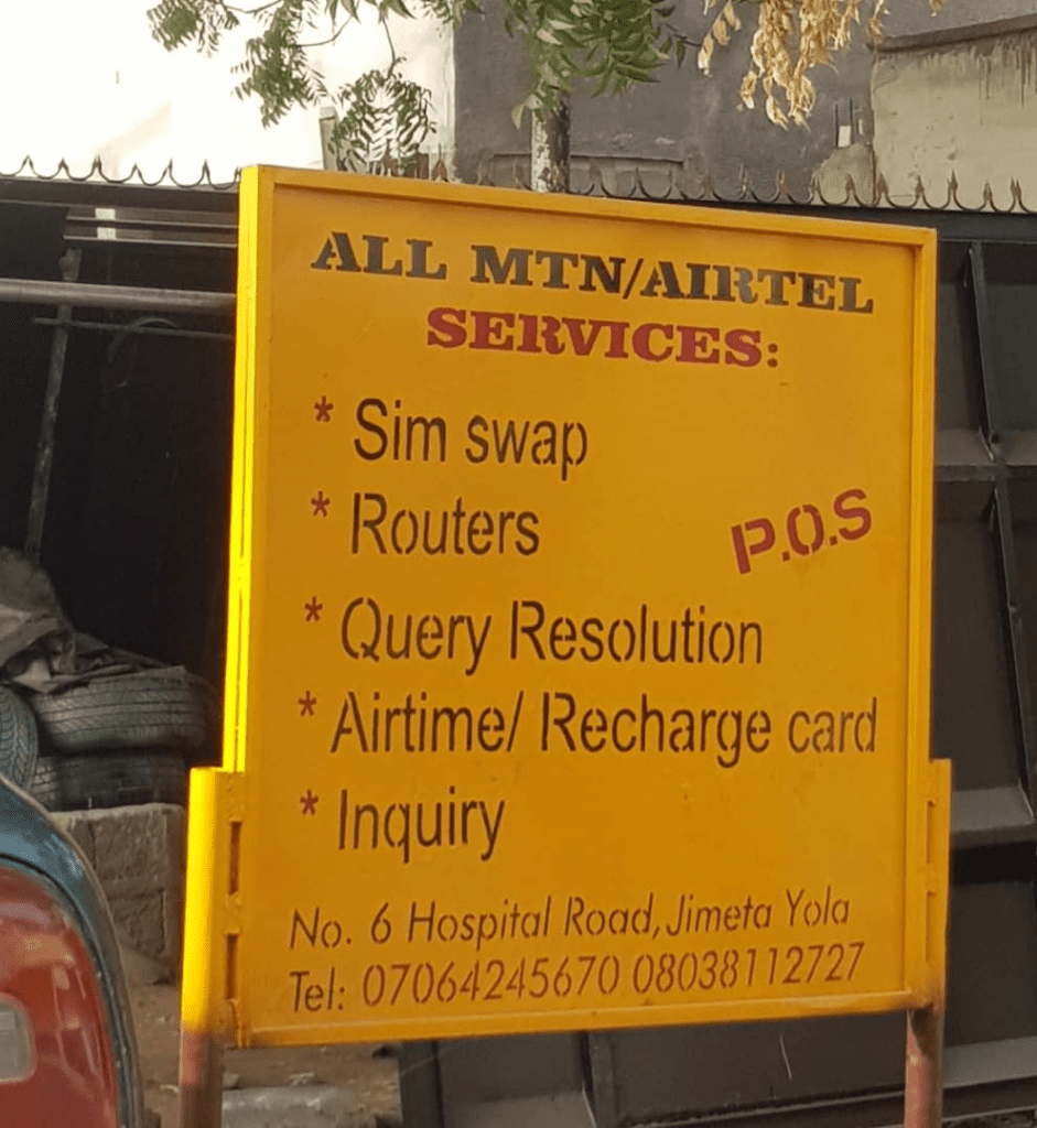 Yellow sign for MTN/Airtel services, including SIM swap, query resolution, and more, located at Hospital Road, Jimeta Yola.