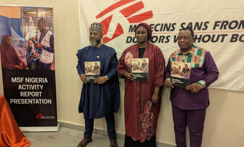 Three people stand holding MSF Nigeria activity reports in front of a banner. A sign reads "MSF Nigeria Activity Report Presentation."