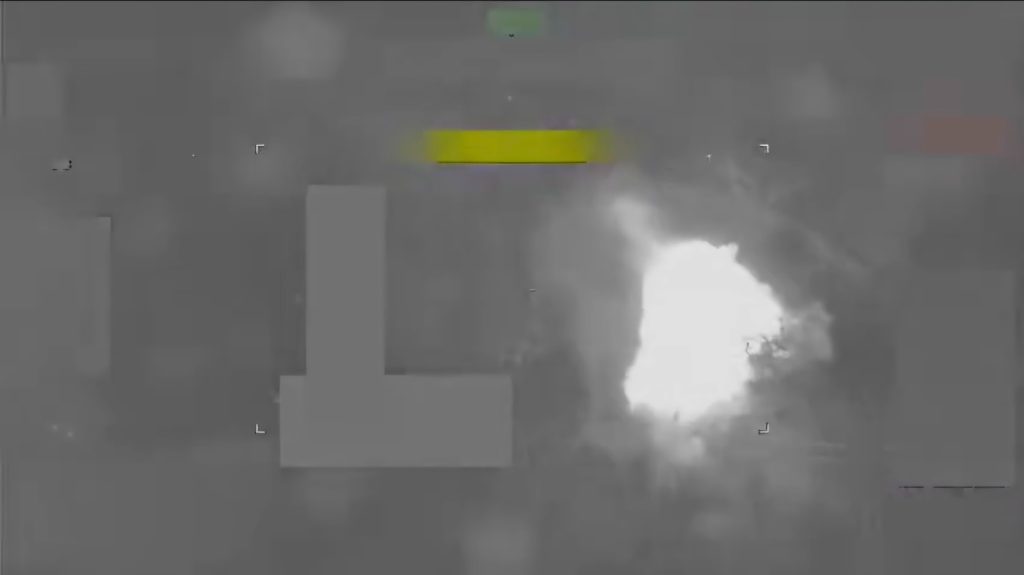 Aerial thermal image showing a bright white explosion against a dark background.