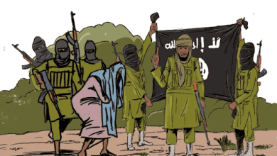 Militants wearing masks, holding weapons and a flag, with one person crouching in front. Background shows greenery.