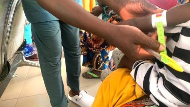 Healthcare worker measuring a child's arm circumference with a tape for nutritional assessment.