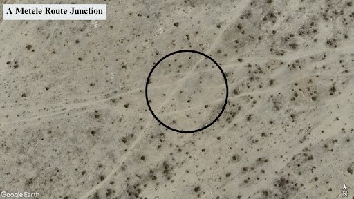 Aerial view showing a Metele Route Junction, marked with a circle, on a rugged, desert-like terrain.